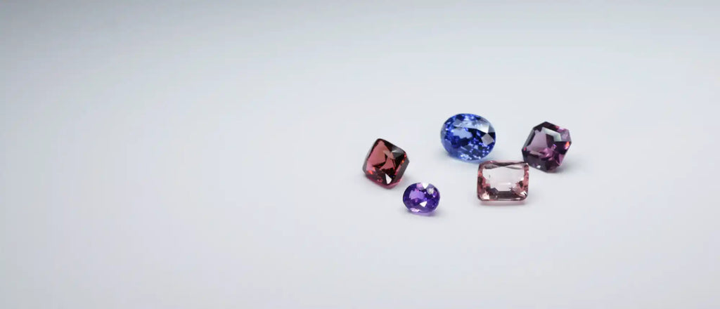Colorful gemstones scattered together, including blue, red, and purple specimens.