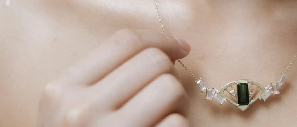 Delicate silver necklace with a green gemstone centerpiece and wing-like designs.