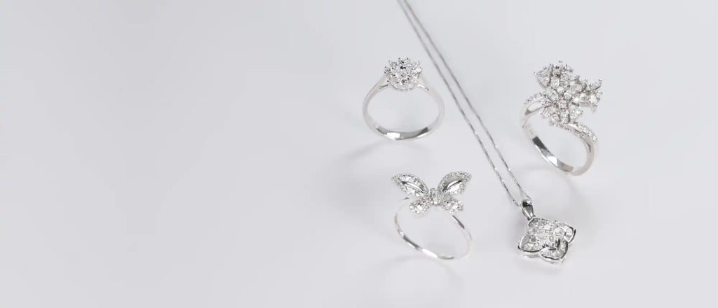 Four silver rings with crystal or diamond embellishments arranged on a surface.